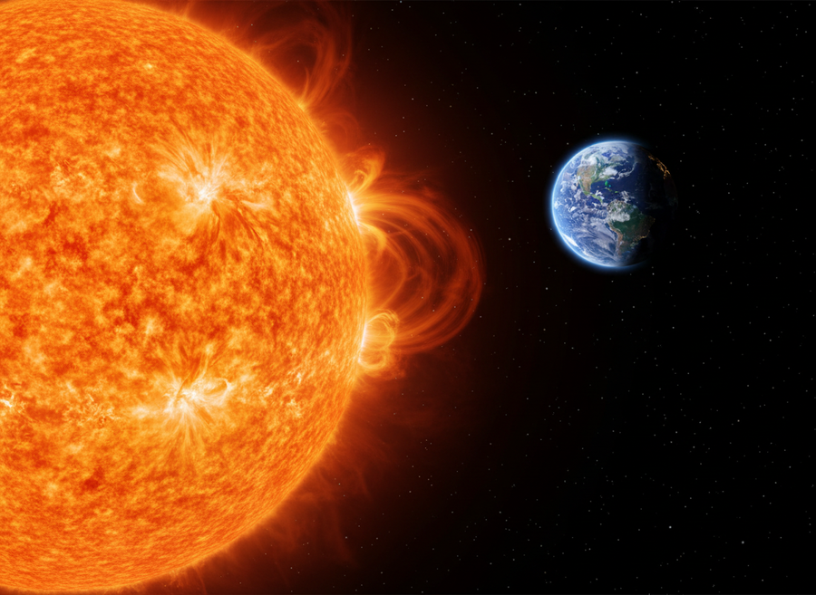 A realistic depiction of the Sun, showing its fiery surface and solar flares, with Earth visible in the distance for scale. No cartoon elements, no text.